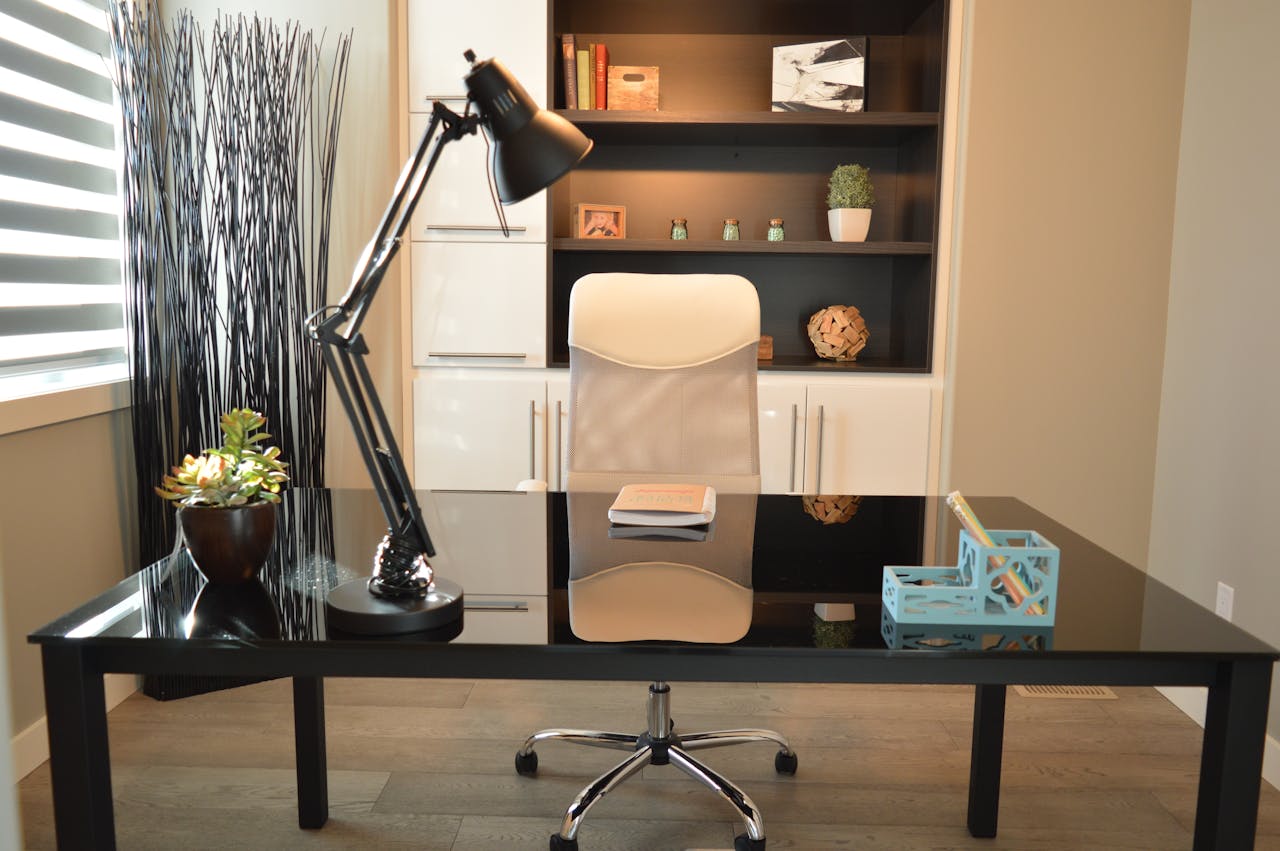 Services-03 Stylish modern office workspace featuring a black desk, lamp, and white chair with shelving.